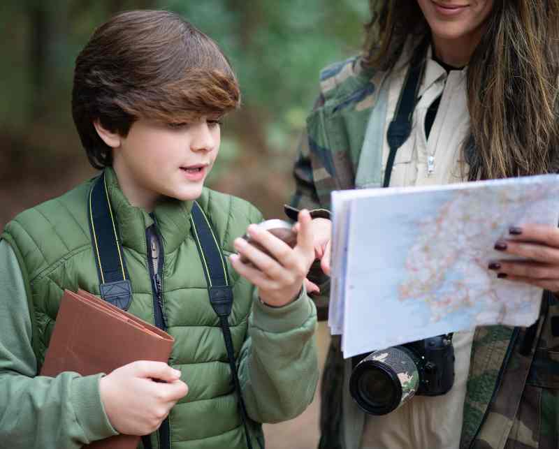Happy kid and mom reading map while hiking.